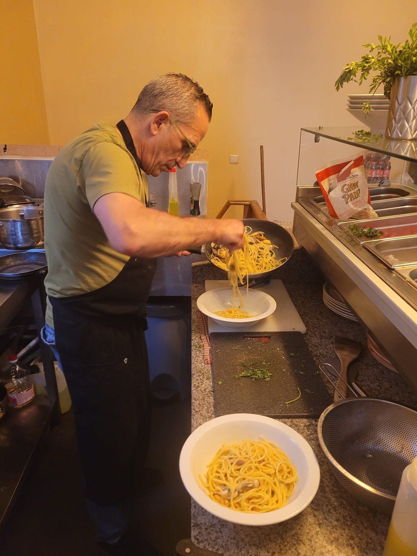 Le chef dresse une assiette de pâtes en cuisine