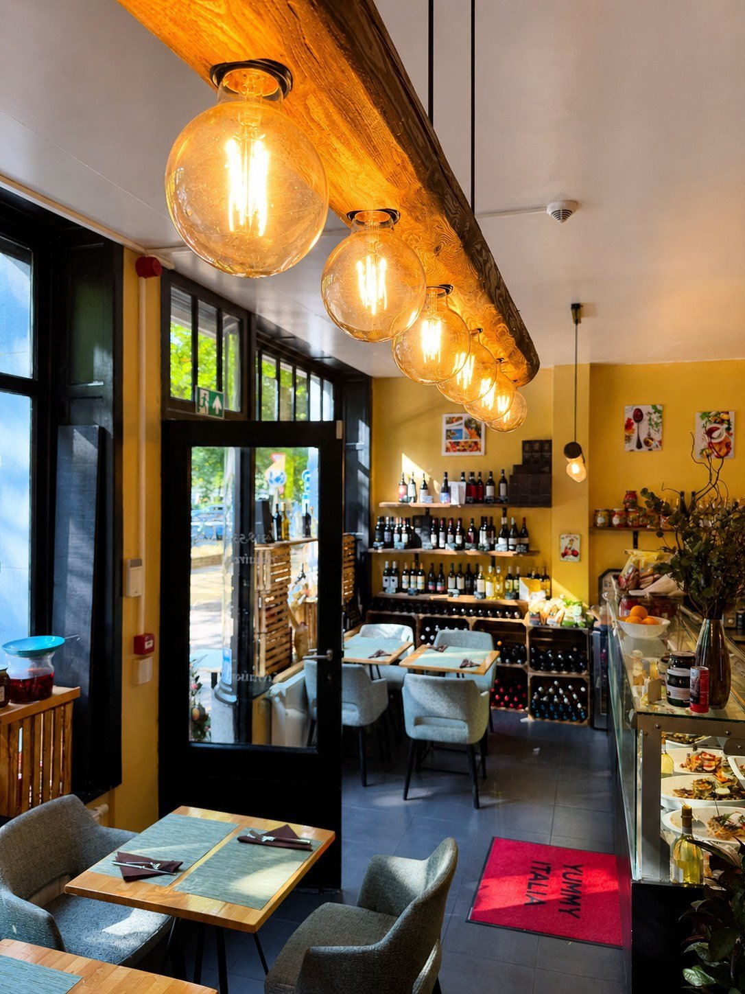 La salle de Yummy Italia : tables, cave à vins et comptoir traiteur